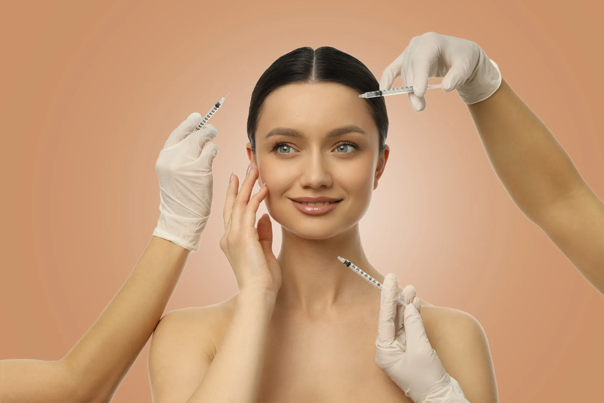 Smiling woman surrounded by gloved hands holding syringes pointed at her face